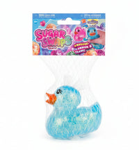 A packaged blue iridescent squeeze rubber duck toy in a clear mesh bag with a printed header card reading Sugar Swops Duck, placed on a speckled light surface.
