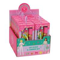 A pink retail display box containing multiple lip gloss and charm sets. Each set includes a pink tube of gloss and a small charm with pastel beads, shown in a branded pink box with cartoon illustrations and the text 'Lip Gloss & Charm Set'.
