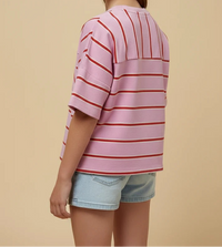 Young girl wearing a pink and red striped shirt with denim shorts on a beige background