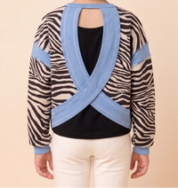 Person wearing a sweater with zebra pattern and blue accents on a beige background