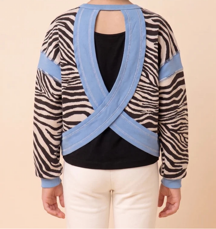 Person wearing a sweater with zebra pattern and blue accents on a beige background