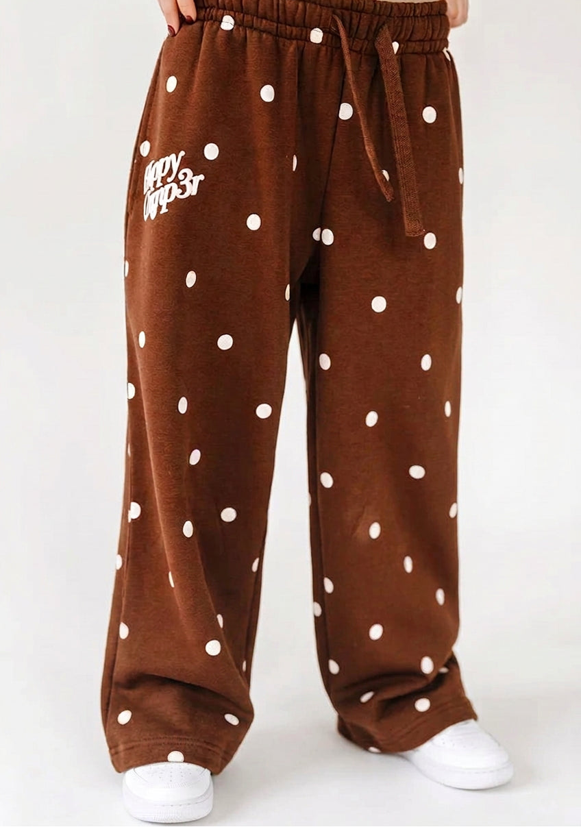 Brown pants with white polka dots worn by a person on a white background