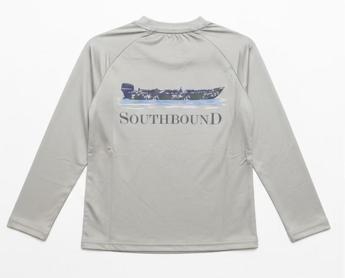 A light gray long-sleeve raglan shirt hanging on a clear hanger, showing the back with a dark blue boat graphic and the word SOUTHBOUND printed across it. A person's hand with purple nail polish and gold bracelets is holding the collar.
