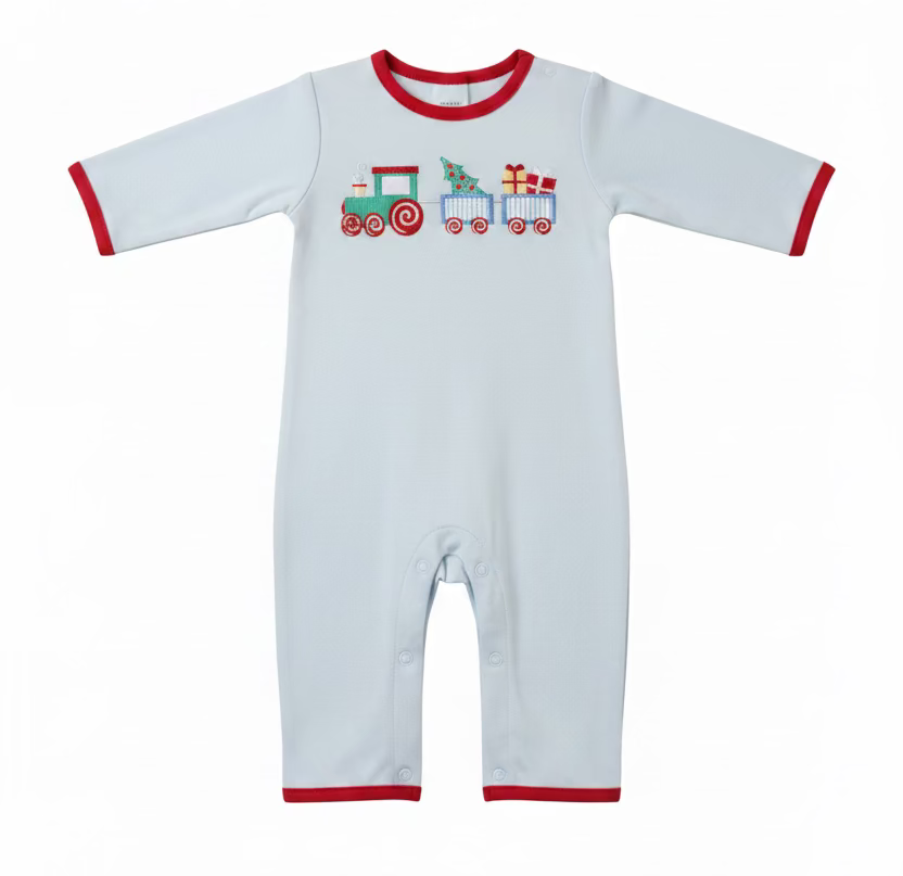 A baby long-sleeve romper in light blue with red trim and a colorful train graphic on the chest, laid flat on a white surface with a hanger. A green baseball cap, folded blue clothing, and a Caddie brand tag are visible around it.