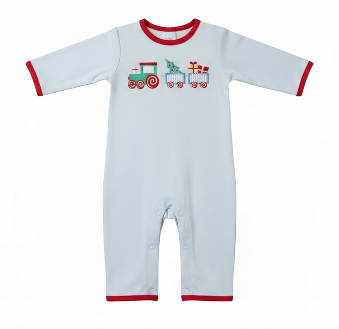A baby long-sleeve romper in light blue with red trim and a colorful train graphic on the chest, laid flat on a white surface with a hanger. A green baseball cap, folded blue clothing, and a Caddie brand tag are visible around it.