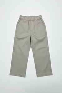 A pair of light beige wide-leg cropped pants hanging on a clear plastic hanger from a store display shelf, with shoe boxes stacked behind them.