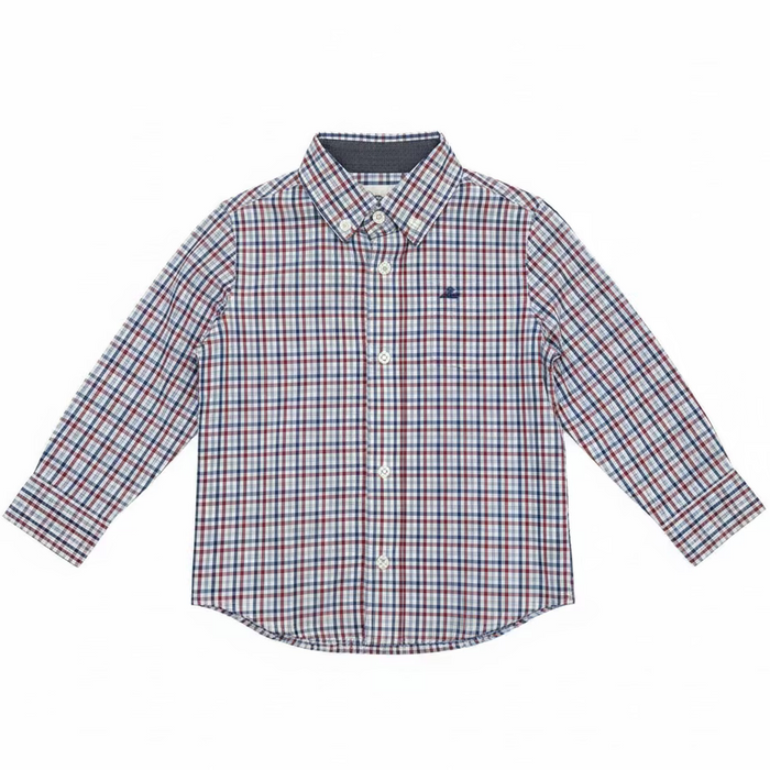 A long-sleeve button-up shirt for kids, featuring a red, white, and blue gingham pattern, hanging on a metal rack in front of shelves filled with shoe boxes.