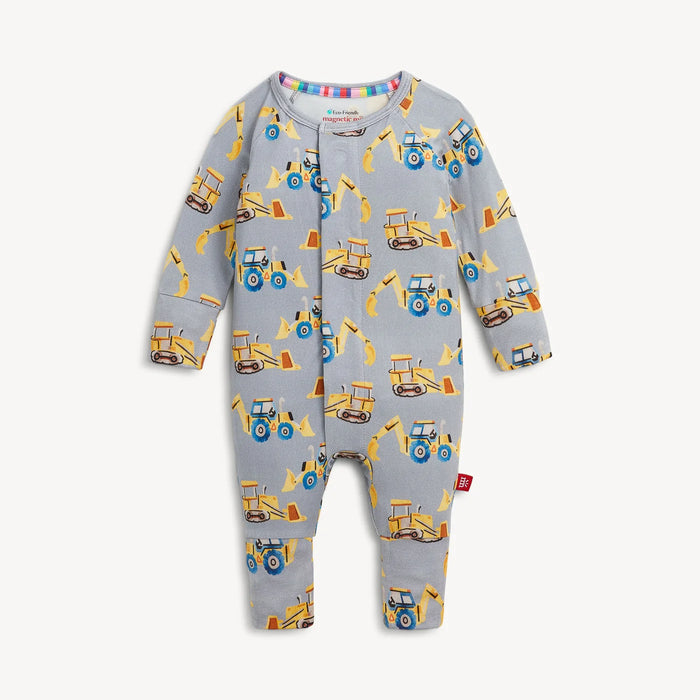 A baby long-sleeve footless one-piece jumpsuit in light gray with an all-over construction vehicle print, featuring yellow bulldozers, tractors, and excavators with blue wheels. The brand name 'Kingsnorth' is visible on the inner neck label.