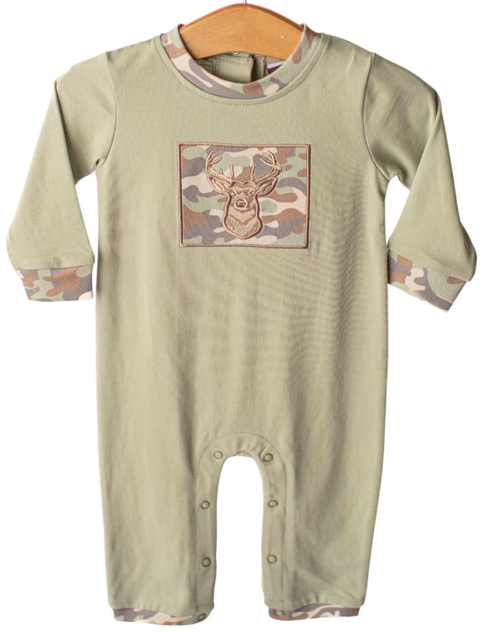 A baby long-sleeve romper in sage green, featuring a camouflage chest graphic with a deer head and matching camouflage cuffs and hem, hanging on a wooden hanger against a white background.