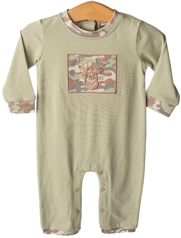 A baby long-sleeve romper in sage green, featuring a camouflage chest graphic with a deer head and matching camouflage cuffs and hem, hanging on a wooden hanger against a white background.