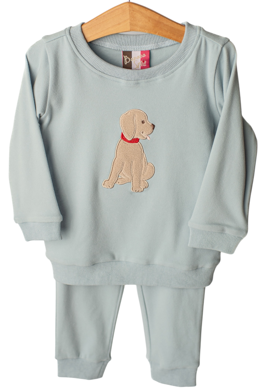 A toddler's two-piece sweatshirt and pants set in a pale sage green, featuring an embroidered puppy on the chest. The set is displayed on a wooden hanger against a plain white background.