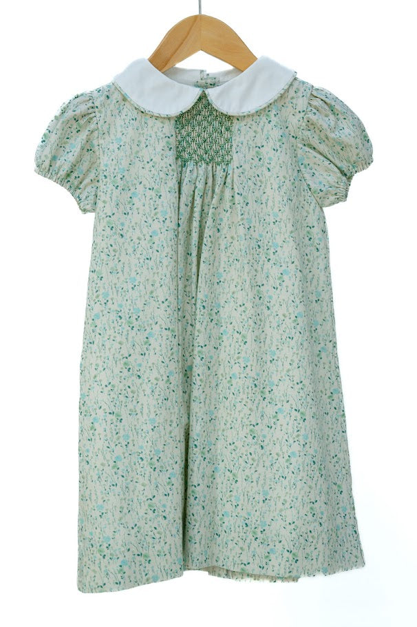 Green floral dress with white collar on a wooden hanger against a white background