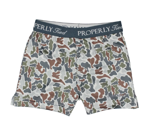 A pair of boxer briefs by Properly Tied, featuring a multi-colored camouflage pattern in green, brown, gray, and white, with a navy blue elastic waistband displaying the brand name.