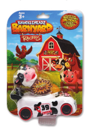 A packaged toy car featuring a pink-and-black cow body with black wheels, mounted on a colorful blister card with a red barn, cartoon animals, and the text 'Wheels Chazz's Barnyard Races.'.
