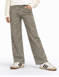 A person wearing leopard-print wide-leg pants, a cream ribbed sweater, and white sneakers with black stripes, shown from the waist down against a plain white studio background.