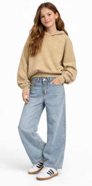A young girl modeling a beige textured hooded sweatshirt, light-wash wide-leg denim jeans, and white Adidas sneakers with black stripes, set against a plain white studio background.