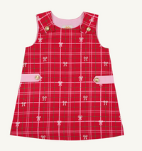 A sleeveless red plaid dress with a pink inner collar, pink buttoned flap pockets, and small bow motifs throughout the fabric, shown flat against a light cream background.