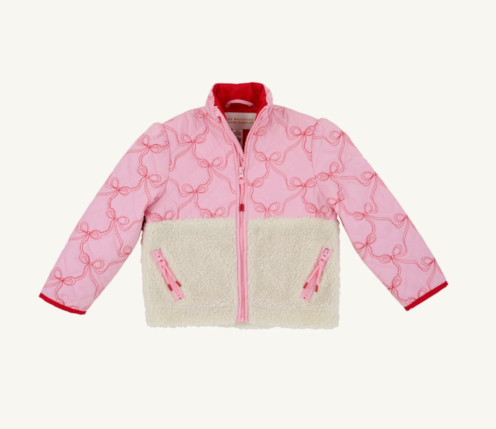 A pink quilted jacket with an allover bow pattern, a cream sherpa fleece lower panel, and red trim, shown flat against a light off-white background.