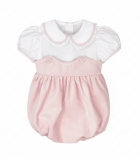 A baby bubble romper dress featuring a white short-sleeve top with a Peter Pan collar and lace trim, paired with a soft pink skirt and button details on the chest, shown against a solid gray background.
