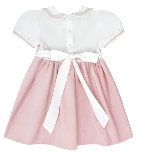 A baby girl's short-sleeve dress with a white batiste and lace bodice, featuring a pink skirt and a large white ribbon bow at the waist, shown against a solid gray background.