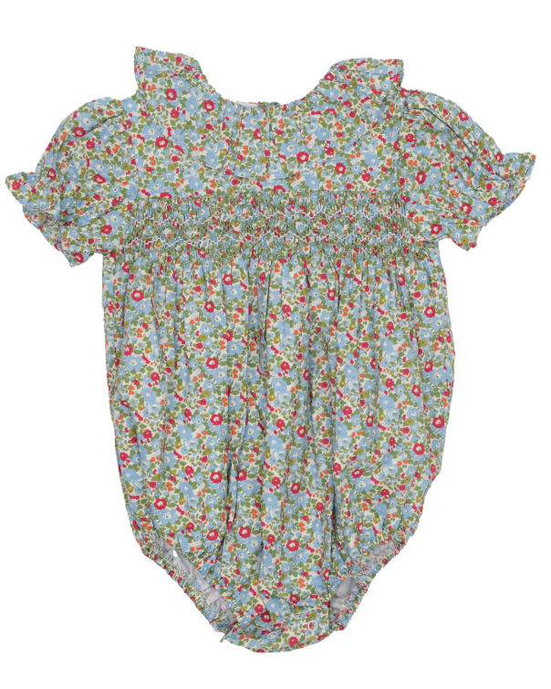 A baby romper with a light blue background and a dense pink, red, and green floral print, featuring ruffled shoulder straps and a smocked waist.