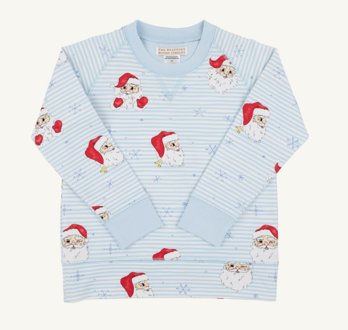 A light blue long-sleeve pajama top with a striped pattern and an all-over print of cartoon Santa Claus faces and red Santa hats, laid flat on a light cream background.