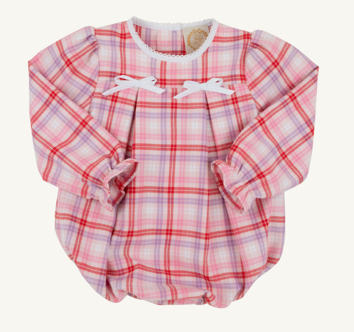 A long-sleeve baby romper in a pink, red, and purple plaid pattern, featuring white lace trim at the collar, white bow details on the chest, and ruffled cuffs, laid flat against a light cream background.