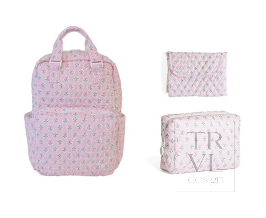 A pink backpack with a small floral pattern is shown alongside matching accessories: a small pouch, a zippered case, and a folded matching item. The backpack has top handles and a front pocket.