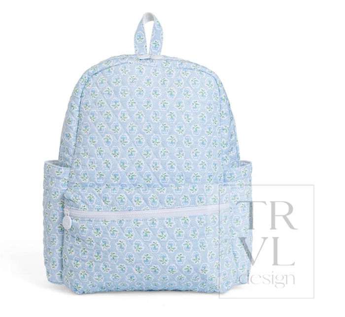 A light blue backpack with a repeating white and green floral pattern, featuring a top handle, a front zippered pocket, and side pockets, shown against a plain white background.