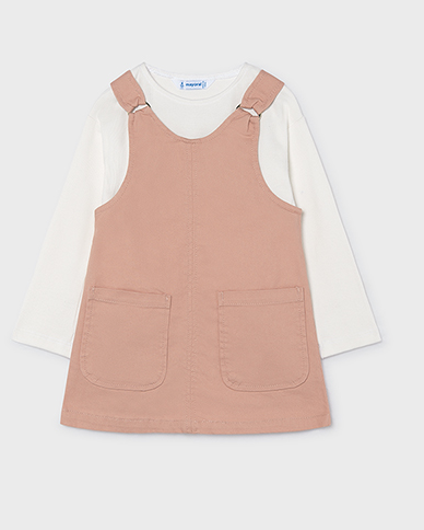 A children's long-sleeve top featuring a dusty pink overall-style bib overlay over a white long-sleeve shirt, shown flat on a light gray background.