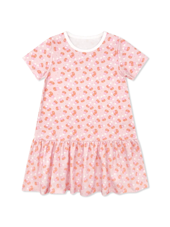 A toddler girl's short-sleeve dress in light pink with a repeating orange and white candy print, featuring a ruffled hem and a white inner collar, shown against a plain white background.
