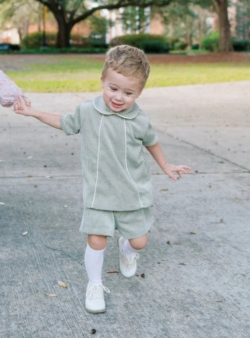 Two children holding hands on a sidewalk with trees in the background