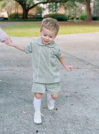 Two children holding hands on a sidewalk with trees in the background