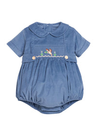 A baby short-sleeve romper in dusty blue corduroy fabric, featuring a Peter Pan collar, a smocked chest panel with a small embroidered bunny and flowers, and two decorative buttons.