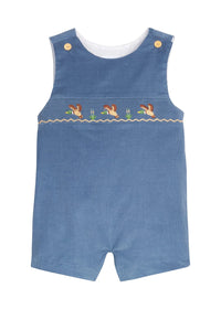 A baby's blue denim smocked romper with embroidered ducks and reeds across the chest, featuring gold snap buttons on the shoulder straps and a white inner collar, shown on a plain white background.