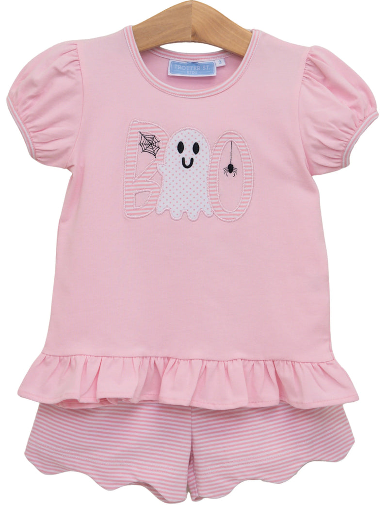 A toddler girl's two-piece pink outfit set featuring a short-sleeve top with a ghost and 'boo' applique design and a matching pink and white striped ruffled shorts set, hanging on a wooden hanger against a white background.