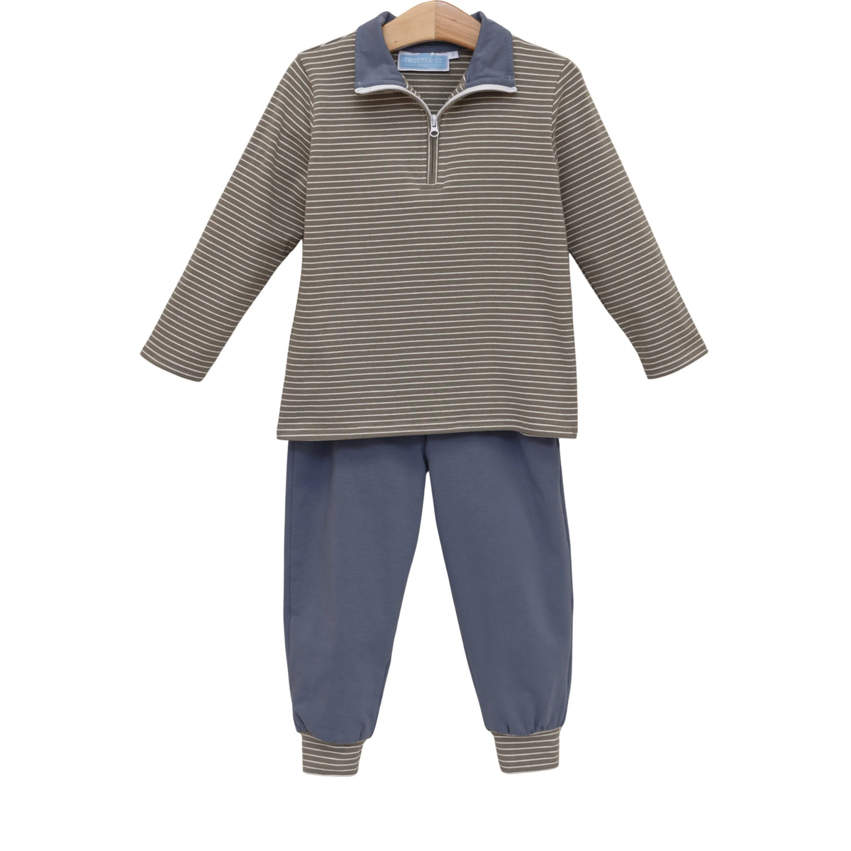A two-piece children's outfit set featuring a long-sleeve quarter-zip pullover top with beige and navy horizontal stripes, and matching navy blue pants with striped cuffs, displayed on a wooden hanger against a white background.