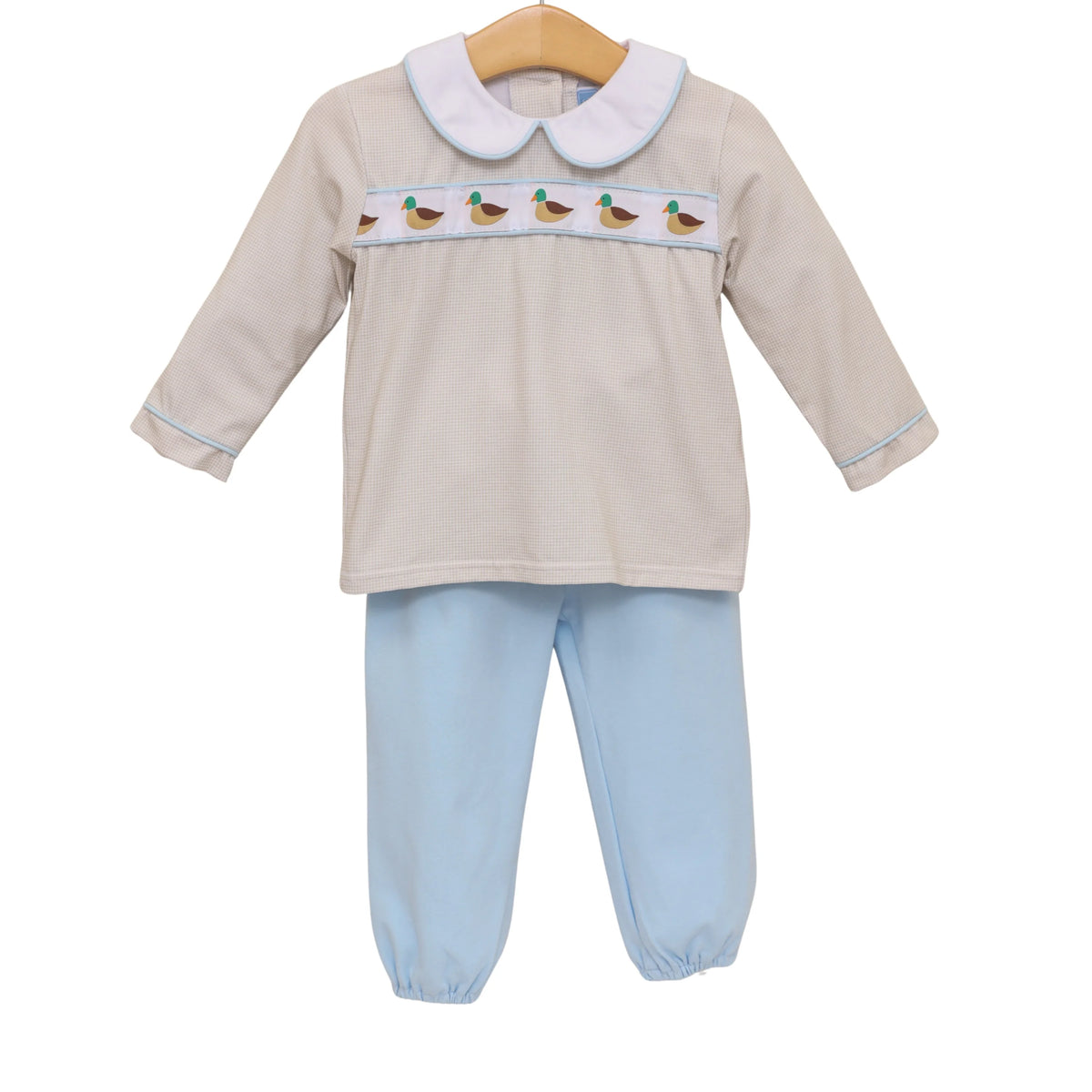 Children's outfit with beige top and light blue pants on a white background