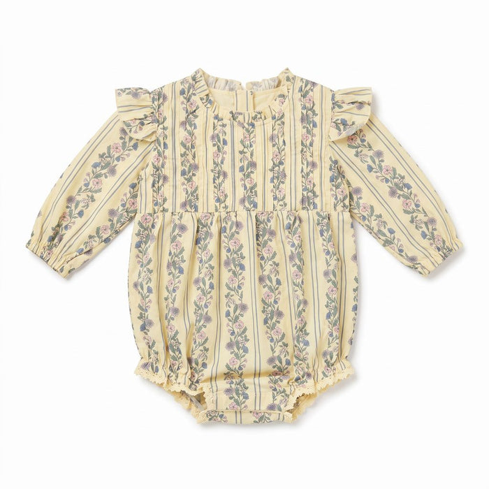 A long-sleeve baby romper in a pale yellowish-beige fabric with vertical stripes and a pink and green floral print, featuring ruffled shoulders and a ruffled leg opening.