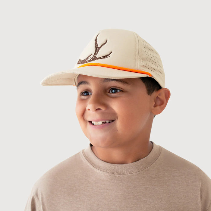 Child wearing a beige cap with deer antlers on a plain background