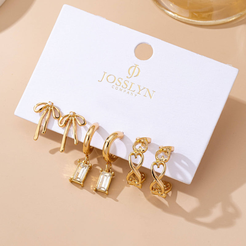 Set of gold earrings on a JOSSLYN branded card against a beige background