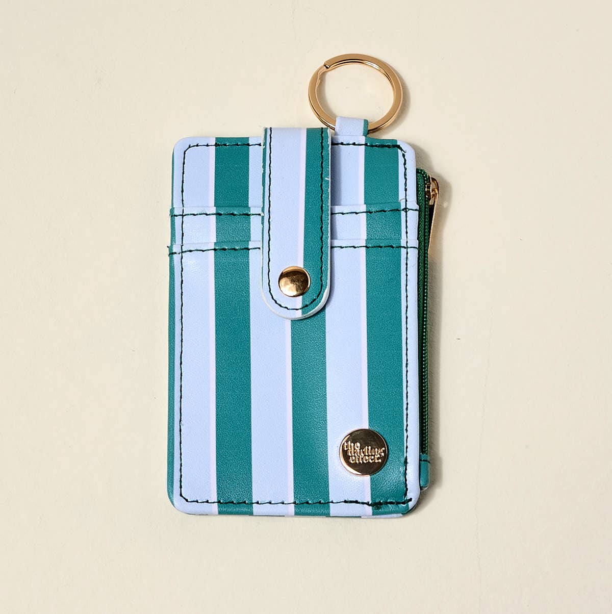 Striped keychain pouch with gold accents on a beige background