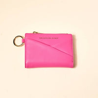 Pink wallet with keychain on a beige background