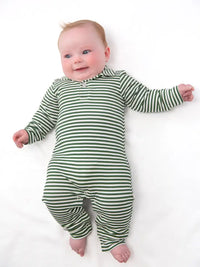 A baby lying on a white background wearing a green and white horizontally striped long-sleeve footless romper.