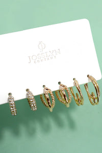 Set of gold hoop earrings on a Jocelyn Company card against a green background