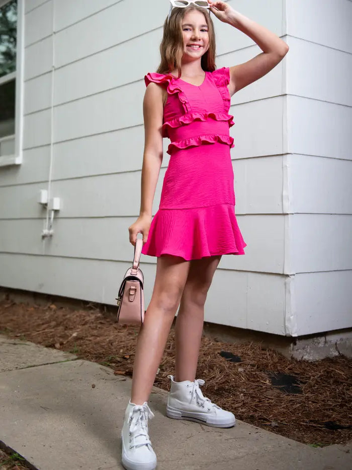 Girl in a pink dress standing outside a building