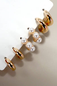 Gold hoop earrings with pearl accents on a white stand.