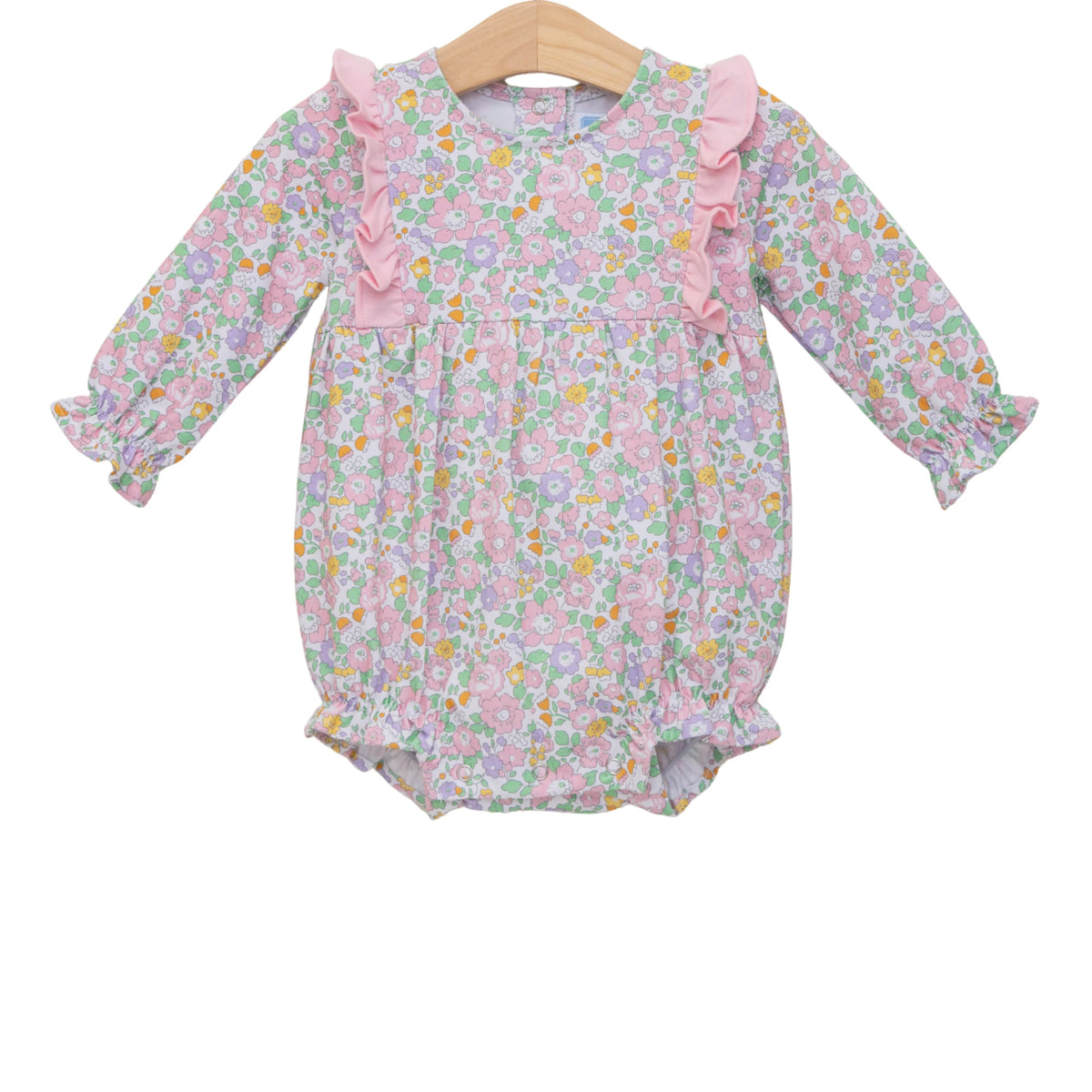 A baby girl's long-sleeve floral romper in pink, purple, and green, featuring ruffle details on the neckline and sleeves, displayed on a wooden hanger against a white background.
