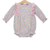 A baby girl's long-sleeve floral romper in pink, purple, and green, featuring ruffle details on the neckline and sleeves, displayed on a wooden hanger against a white background.