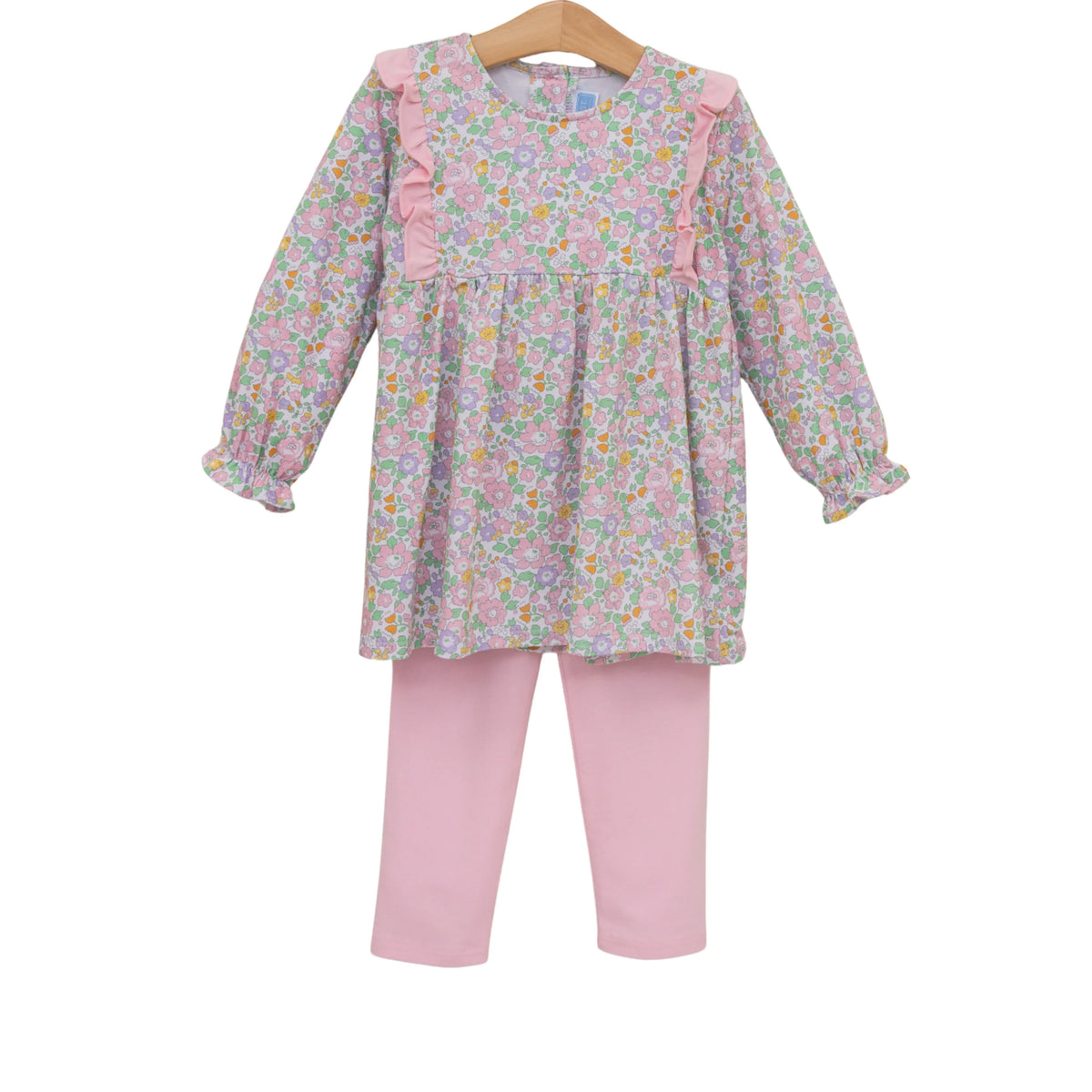 A toddler girl's two-piece outfit set featuring a long-sleeve floral print tunic top with pink ruffle details on the shoulders and sleeves, paired with solid light pink leggings, displayed on a wooden hanger against a white background.